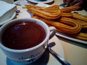 taza de chocolate caliente y un plato de churros al lado