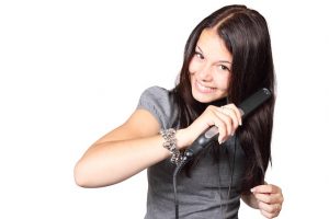 mujer morena planchandose el pelo con una plancha de pelo