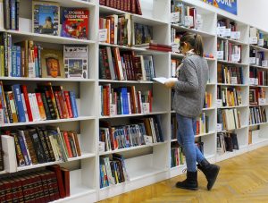 Chica delante de una estantería de libros, leyendo