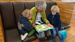 Mujer mayor leyendo a dos niños