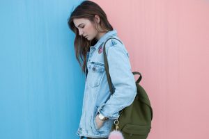 Una chica con chaqueta tejana y bolso verde pantano.