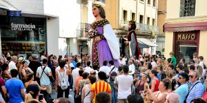 Gigantes caminan por una calle abarrotada de gente