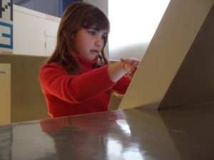 Niña en un museo tocando una pantalla con los dedos.