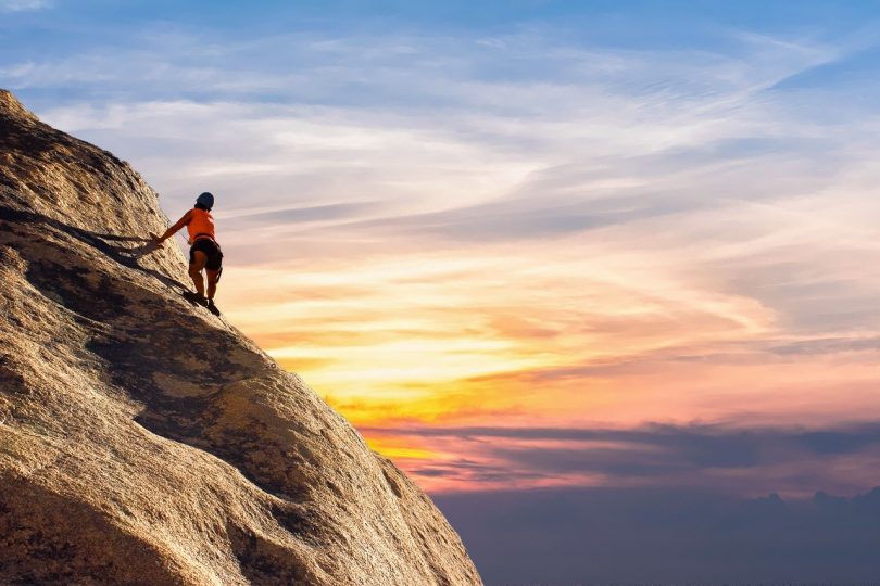 mujer escalando con imagen de puesta de sol