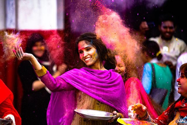 Imagen de una mujer lanzando polvos de colores