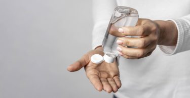 unas manos poniendose gel para manos de un bote transparente