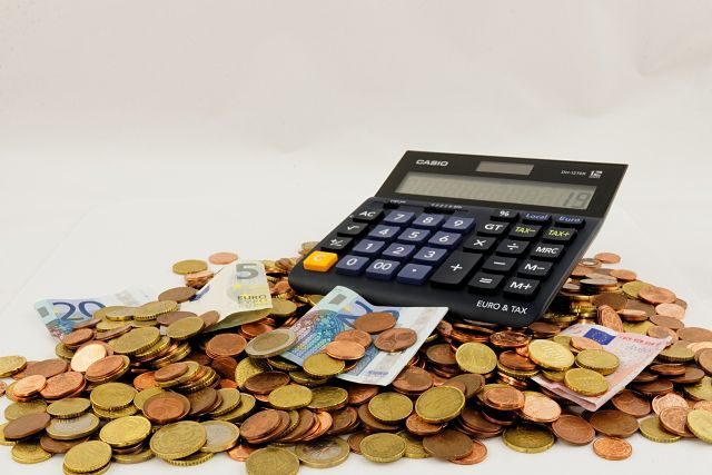 Imagen de un montón de monedas y billetes de euro y una calculadora