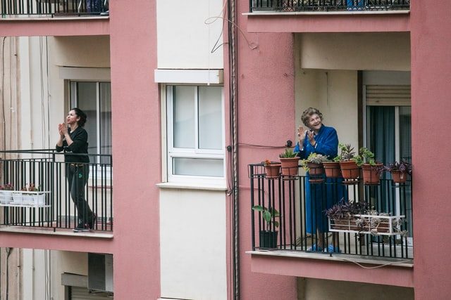 dos mujeres aplaudiendo desde sus balcones