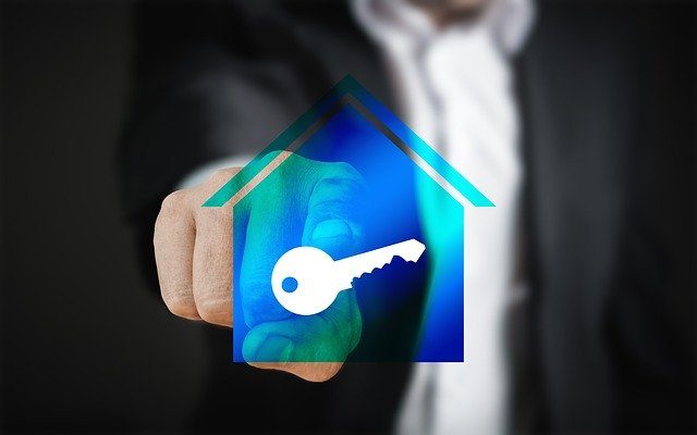 hombre señalando una llave digital dentro de una casa azul 