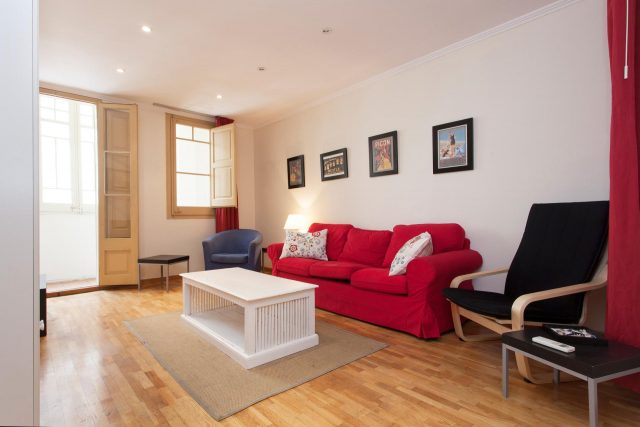 Salón de piso bonito con suelo de madera y sofá rojo