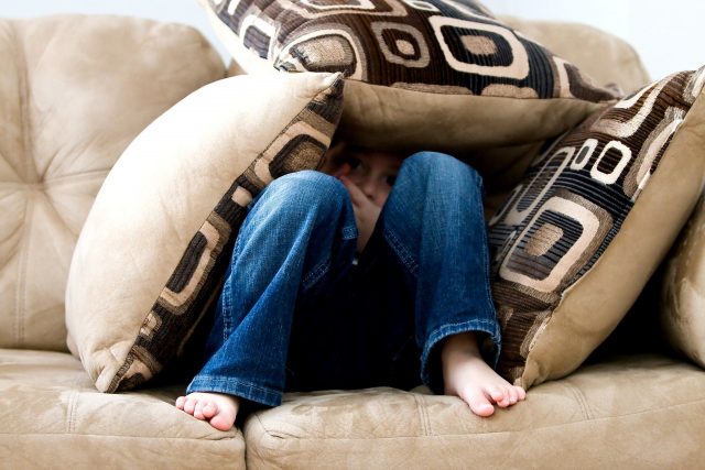 niño escondido en el sofá que no quiere ver maratón de series