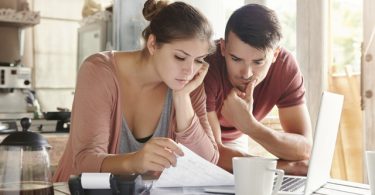 Un chico y una chica revisan un documento con atención.