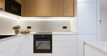 Cocina reformada con muebles blancos y color madera.