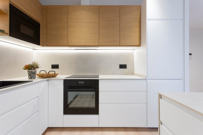 Cocina reformada con muebles blancos y color madera.