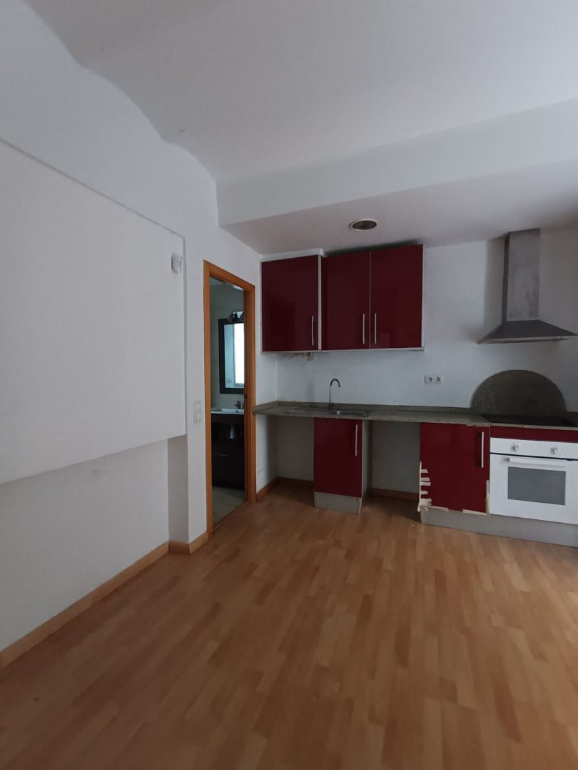 Cocina tipo abierta sin reformar, con suelos de parquet y paredes blancas.