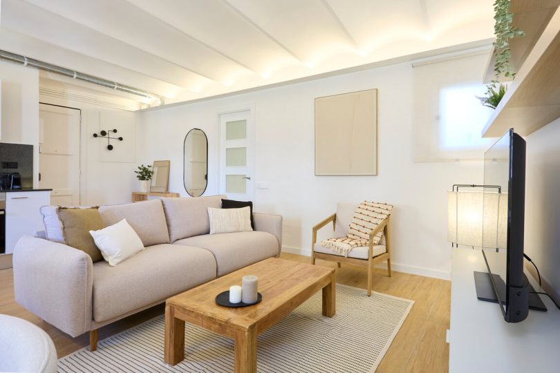 Salón reformado y completamente amueblado con suelo de parquet y colores claros.