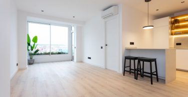 Salón reformado con suelo de parquet y colores claros.