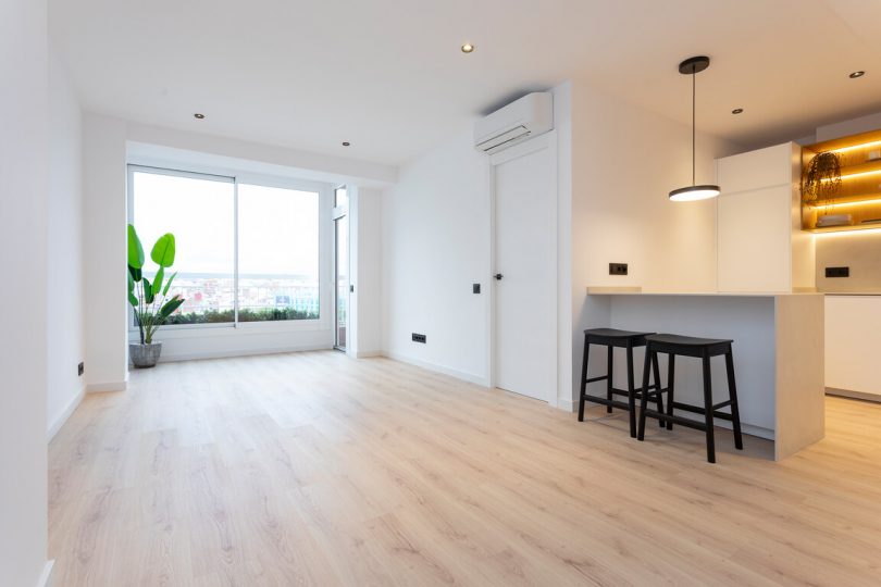 Salón reformado con suelo de parquet y colores claros.